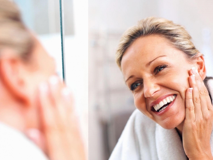 Процедуры после 40. Процедуры после 40. Омоложение лица женщина. Уход за лицом. Женщина мажет лицо кремом.